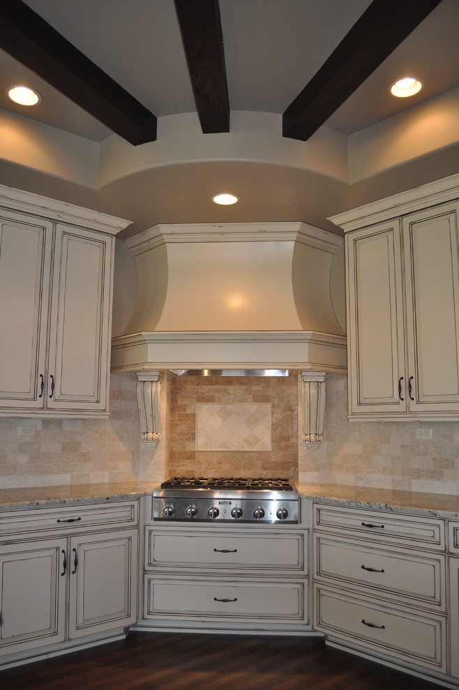 Traditional kitchen in New Orleans with an undermount sink, raised-panel cabinets, light wood cabinets, granite benchtops, white splashback, stone tile splashback, stainless steel appliances, dark hardwood floors and with island.