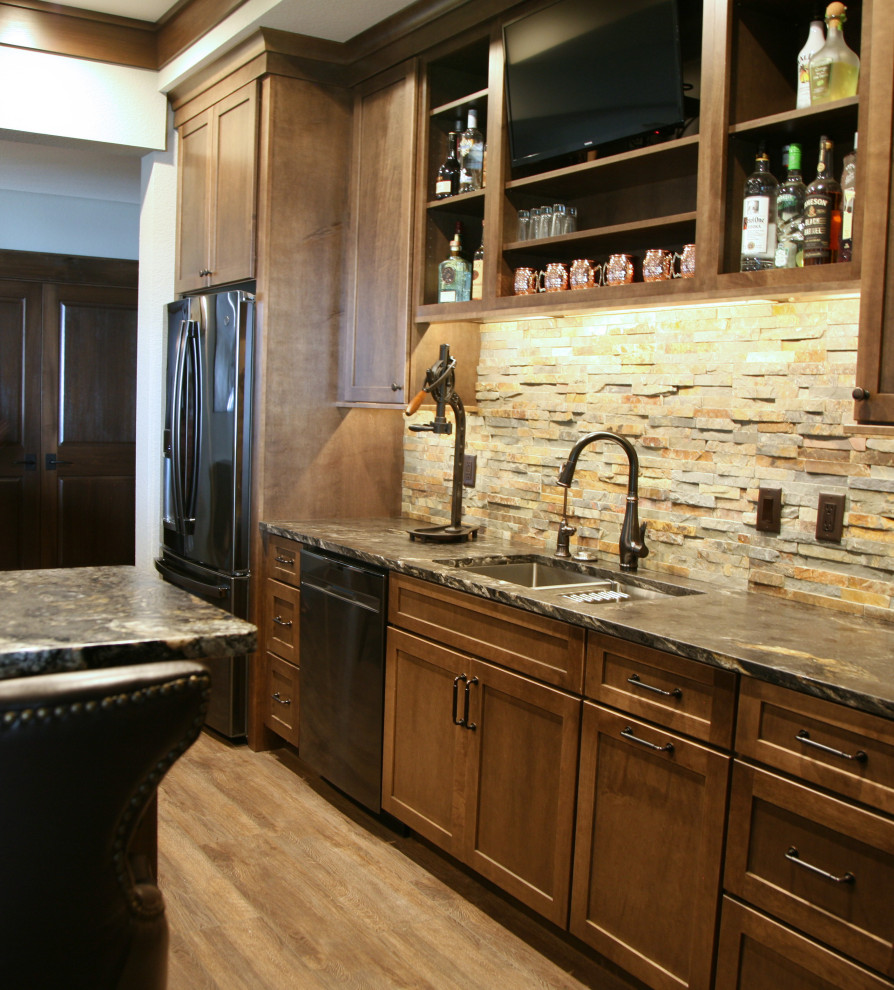 Inspiration for a large traditional single-wall wet bar in Milwaukee with an undermount sink, flat-panel cabinets, medium wood cabinets, granite benchtops, beige splashback, stone tile splashback, vinyl floors, brown floor and black benchtop.