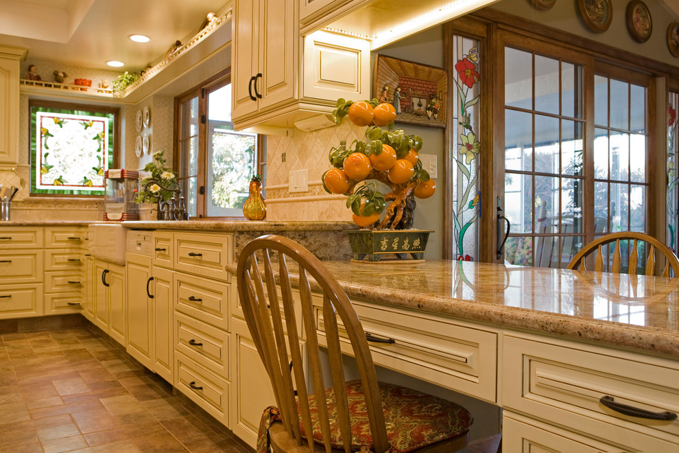 Design ideas for a large traditional u-shaped separate kitchen in San Diego with a farmhouse sink, raised-panel cabinets, yellow cabinets, granite benchtops, beige splashback, stone tile splashback, panelled appliances, porcelain floors and with island.