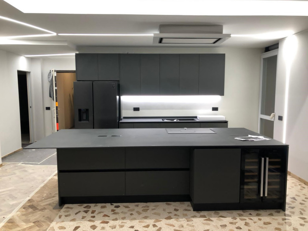 This is an example of a large contemporary galley open plan kitchen in Other with an undermount sink, glass-front cabinets, black cabinets, tile benchtops, black appliances, with island, black benchtop and recessed.