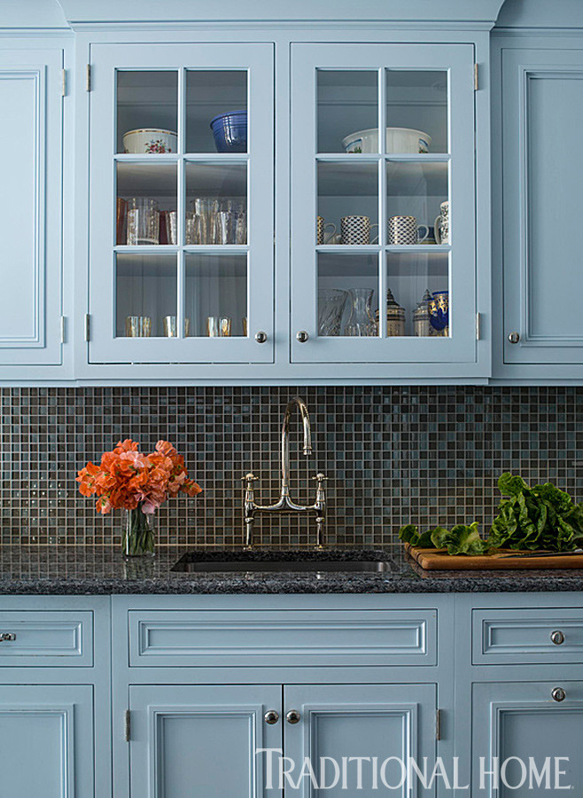 Photo of a small traditional galley kitchen in New York with an undermount sink, louvered cabinets, blue cabinets, granite benchtops, grey splashback, glass tile splashback, panelled appliances and porcelain floors.
