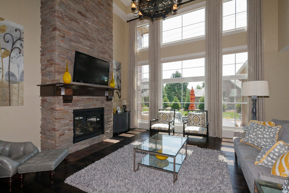 Photo of a large traditional open concept family room in St Louis with beige walls, dark hardwood floors, a standard fireplace and a wall-mounted tv.