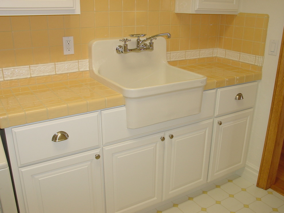Mid-sized traditional galley utility room in Sacramento with a farmhouse sink, raised-panel cabinets, white cabinets, tile benchtops, porcelain floors and a side-by-side washer and dryer.