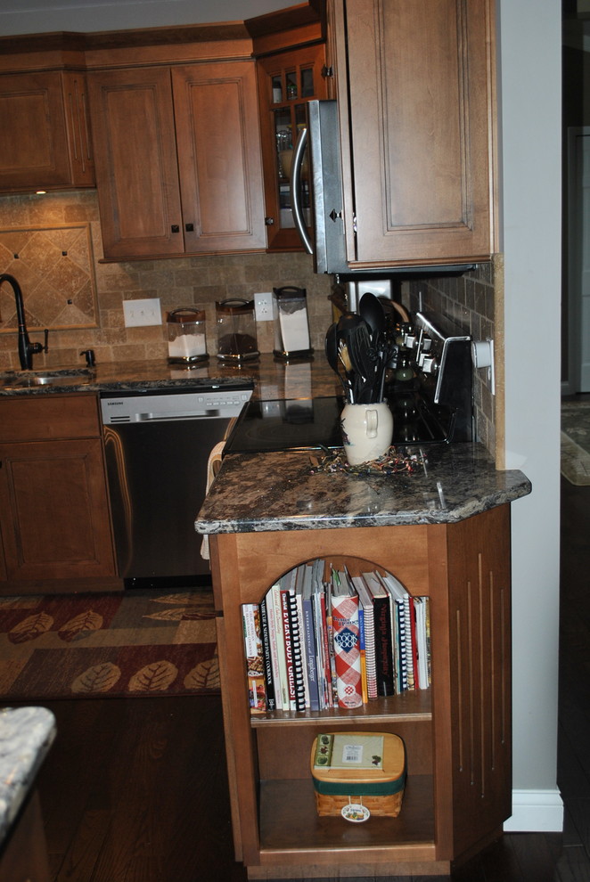 Kitchen - brown floor kitchen idea with brown cabinets, beige backsplash, stainless steel appliances, an island and gray countertops