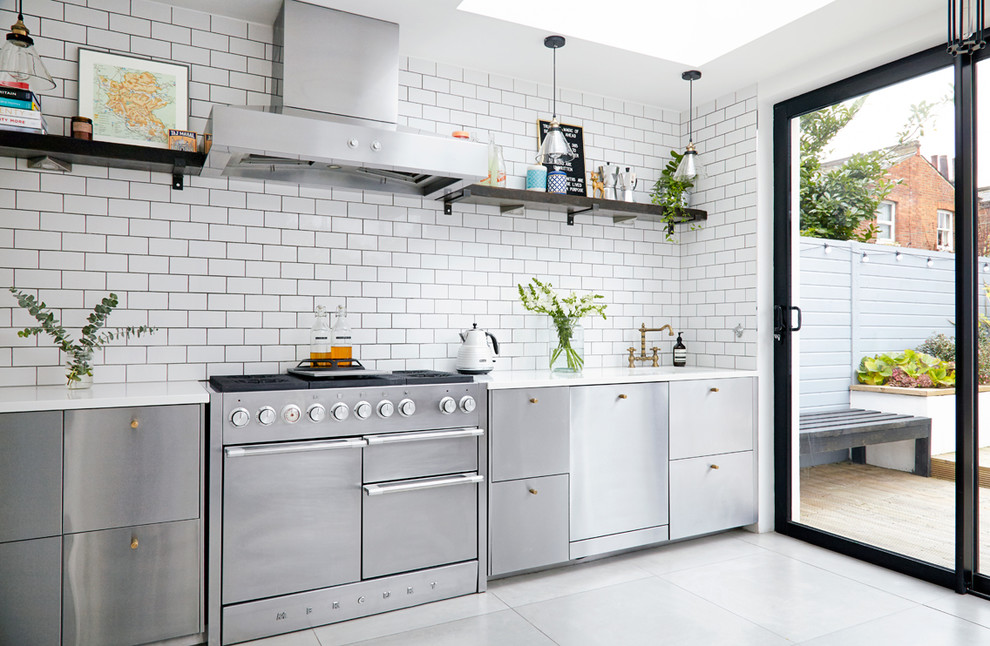 Scandinavian single-wall kitchen in London with an undermount sink, flat-panel cabinets, stainless steel cabinets, white splashback, subway tile splashback and stainless steel appliances.