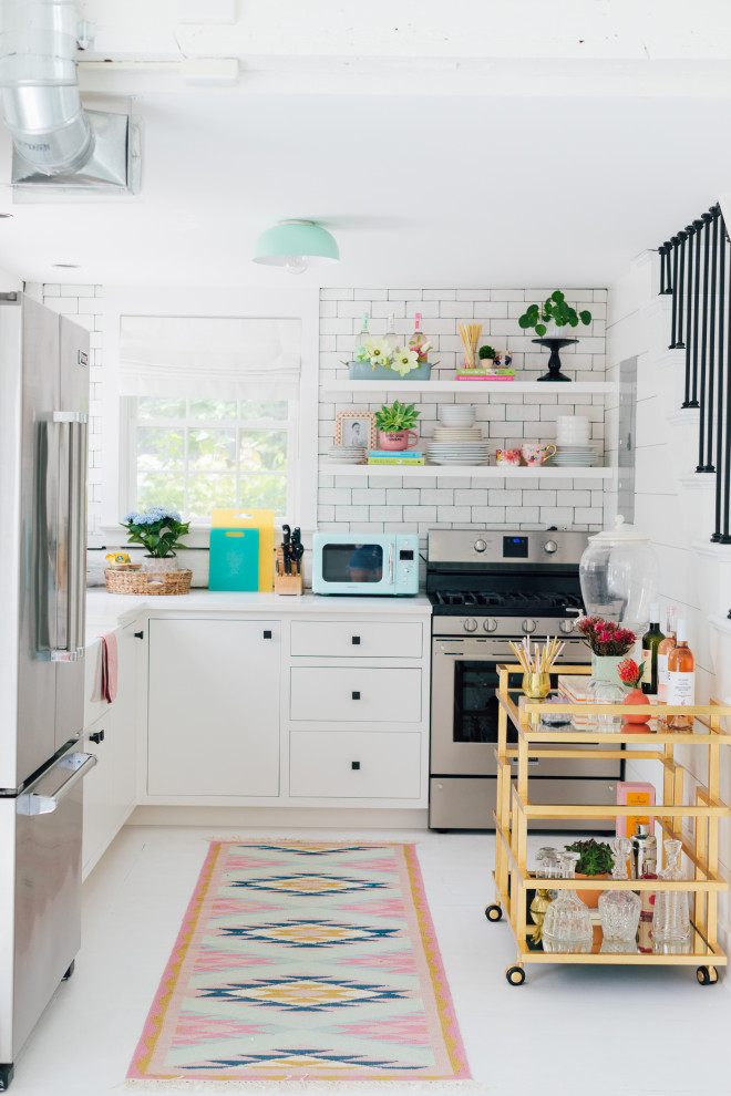 Example of a small l-shaped painted wood floor and white floor kitchen design in New York with a farmhouse sink, flat-panel cabinets, white cabinets, marble countertops, white backsplash, ceramic backsplash, stainless steel appliances, no island and white countertops