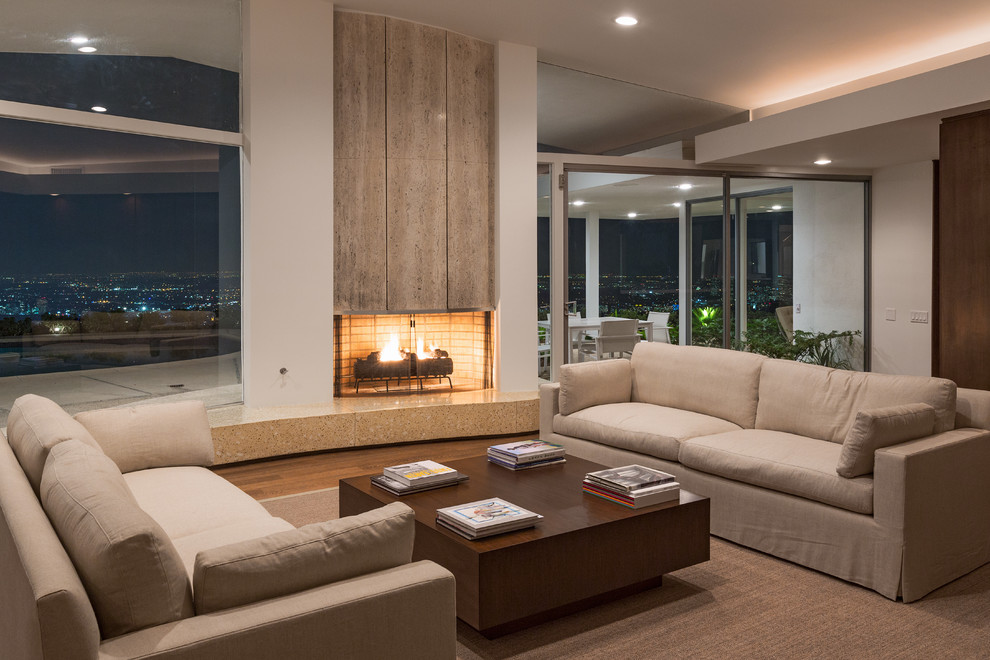 Photo of a midcentury living room in Los Angeles with white walls, dark hardwood floors and a standard fireplace.