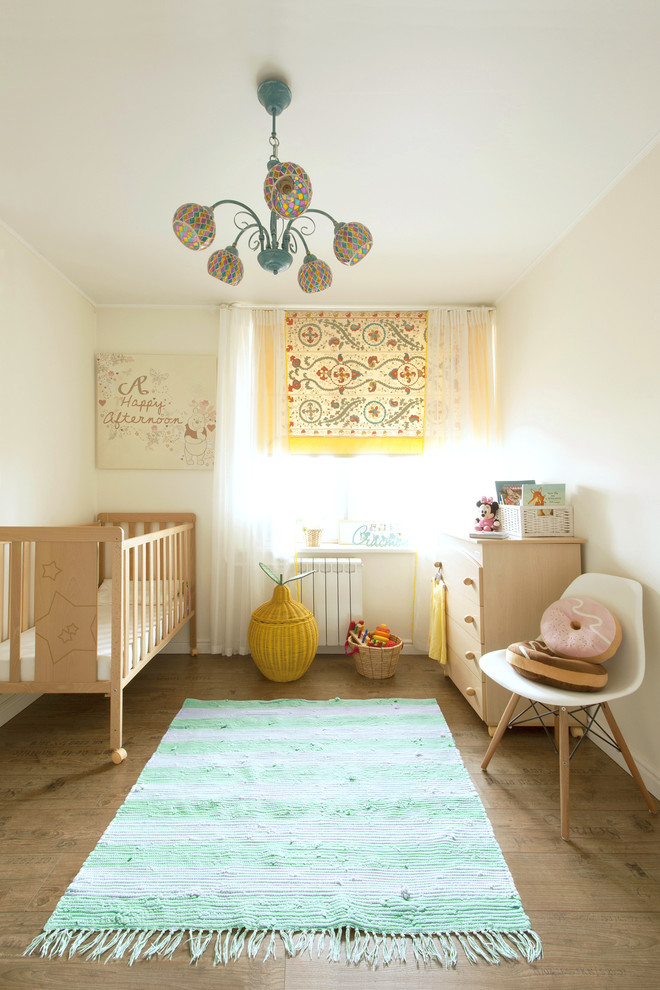 This is an example of a small scandinavian nursery for girls in Moscow with white walls and medium hardwood floors.