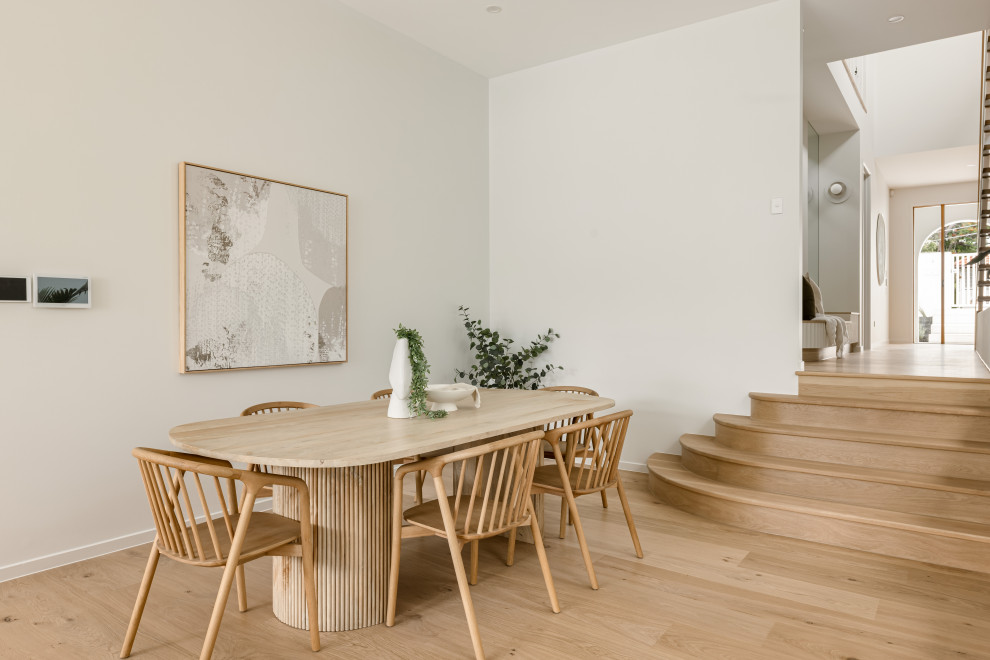 This is an example of a modern dining room in Brisbane with white walls, light hardwood floors and beige floor.