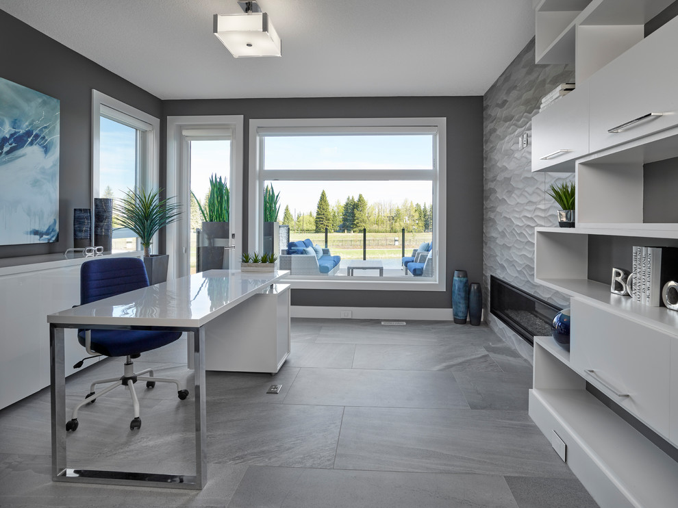 Photo of a large contemporary study room in Edmonton with grey walls, ceramic floors, a two-sided fireplace, a tile fireplace surround, a freestanding desk and grey floor.