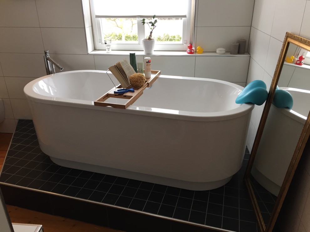 Inspiration for a mid-sized contemporary 3/4 wet room bathroom in Other with a freestanding tub, a two-piece toilet, white tile, white walls, light hardwood floors, tile benchtops and a trough sink.
