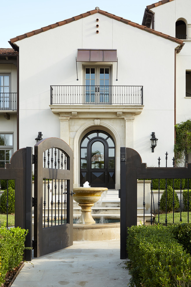Expansive mediterranean two-storey stucco white house exterior in Houston with a gable roof and a tile roof.