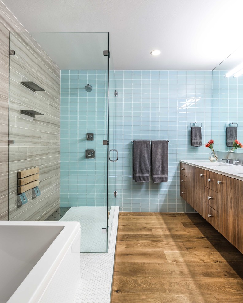 Example of a 1950s blue tile and subway tile medium tone wood floor drop-in bathtub design in Austin with flat-panel cabinets, blue walls and a hinged shower door