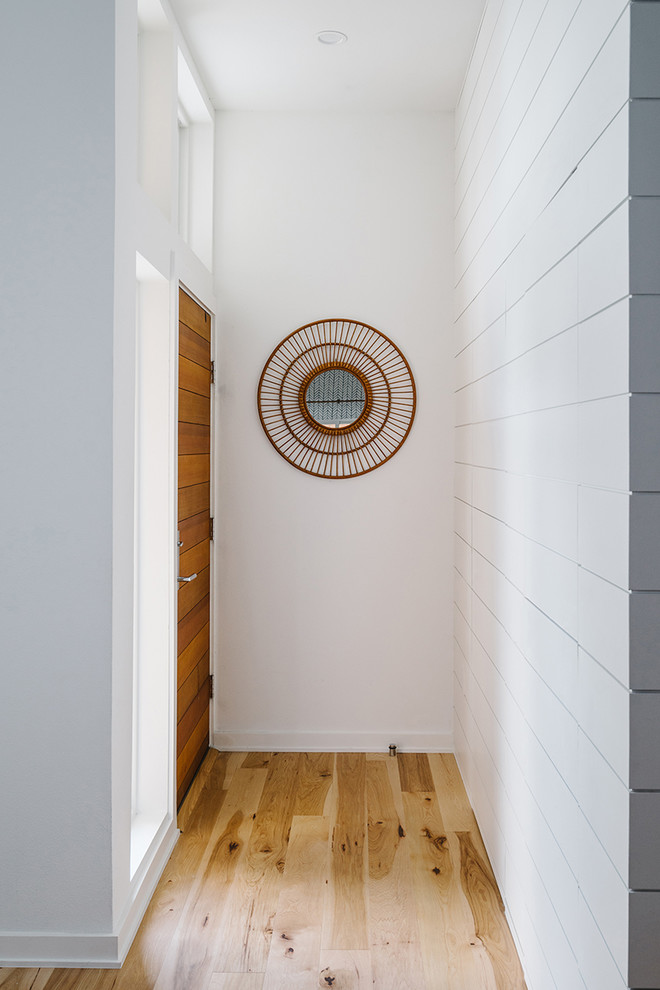 Design ideas for a mid-sized scandinavian hallway in Austin with white walls and light hardwood floors.