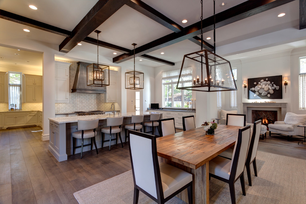 This is an example of a large mediterranean open plan dining in Dallas with white walls, dark hardwood floors, a standard fireplace, a concrete fireplace surround and white floor.