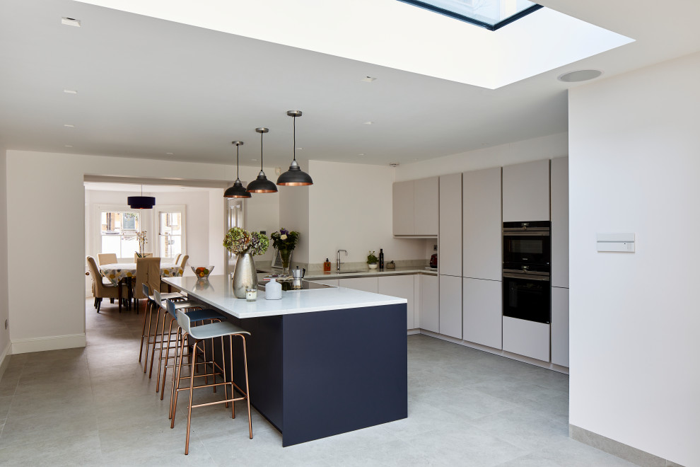 Inspiration for a large modern l-shaped open plan kitchen in London with a single-bowl sink, flat-panel cabinets, white cabinets, marble benchtops, white appliances, a peninsula, white benchtop and coffered.