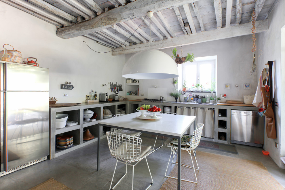This is an example of a mediterranean l-shaped eat-in kitchen in Milan with a drop-in sink, open cabinets, grey cabinets, concrete benchtops, white splashback, stainless steel appliances, concrete floors, no island, grey floor and grey benchtop.