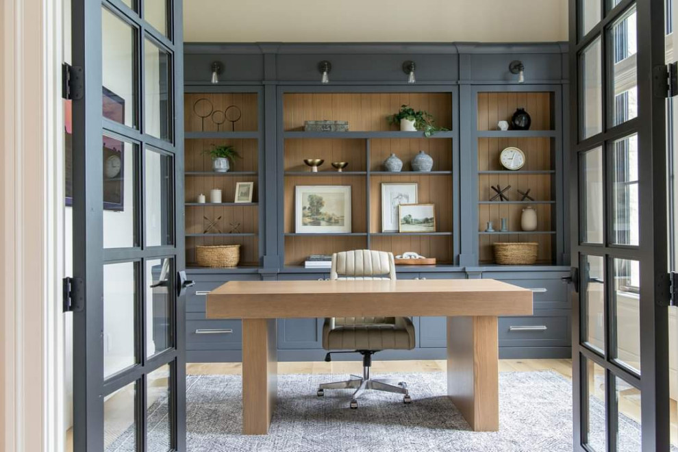 Imagen de despacho tradicional renovado de tamaño medio con paredes beige, suelo de madera clara, escritorio independiente y vigas vistas