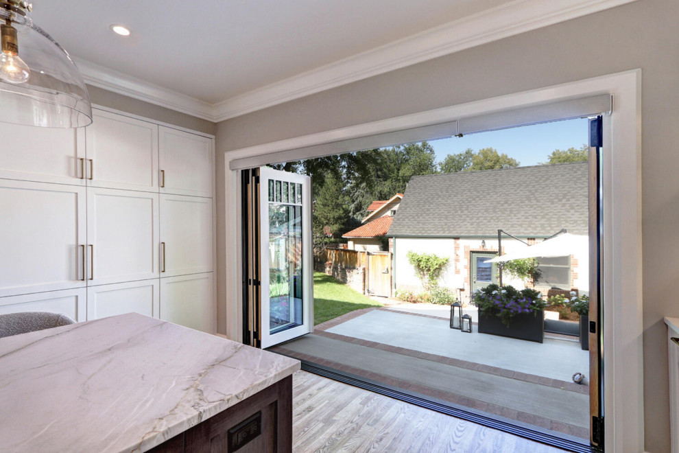 Enclosed kitchen - mid-sized transitional u-shaped medium tone wood floor and brown floor enclosed kitchen idea in Denver with an undermount sink, recessed-panel cabinets, white cabinets, marble countertops, white backsplash, ceramic backsplash, paneled appliances, an island and white countertops