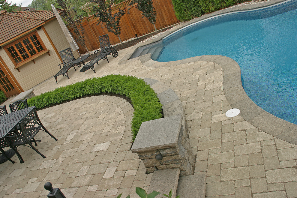 Design ideas for a mid-sized transitional backyard kidney-shaped lap pool in Toronto with a pool house and concrete pavers.