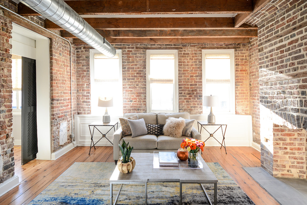 Photo of an industrial formal enclosed living room in Charleston with multi-coloured walls, medium hardwood floors, a standard fireplace, a brick fireplace surround and brown floor.