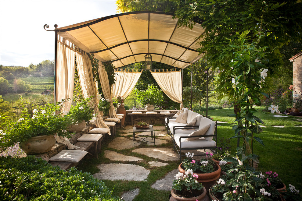 Large country patio in Venice with natural stone pavers, a container garden and an awning.
