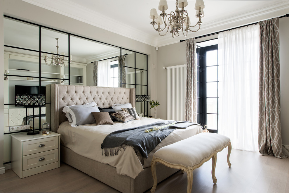 Photo of a transitional master bedroom in Moscow with beige walls and light hardwood floors.