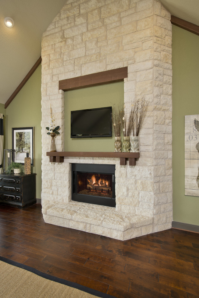 Inspiration for a large traditional living room in Houston with green walls, medium hardwood floors, a standard fireplace, a stone fireplace surround, a wall-mounted tv and brown floor.