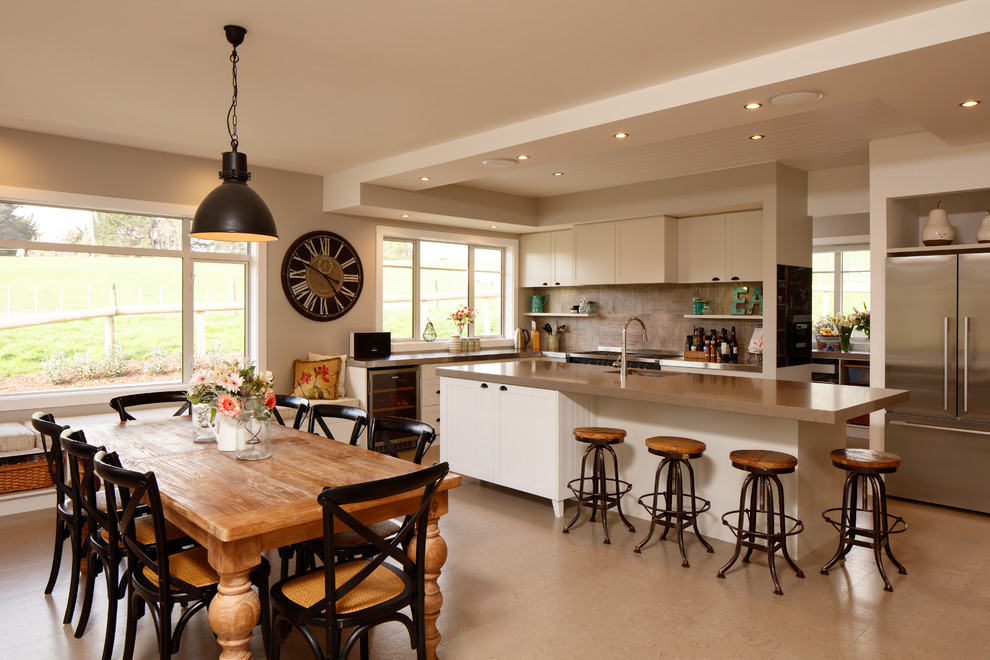 Inspiration for a large country galley eat-in kitchen in Wellington with a farmhouse sink, recessed-panel cabinets, white cabinets, stainless steel benchtops, stone tile splashback, stainless steel appliances, cork floors, with island and beige floor.