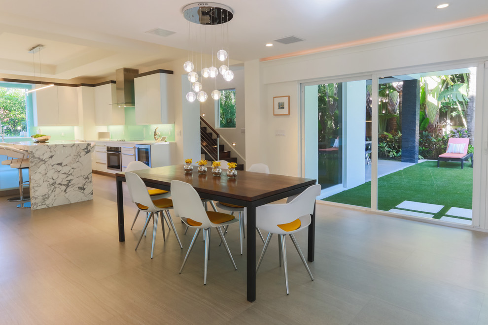 Photo of a large modern u-shaped eat-in kitchen in Miami with an undermount sink, flat-panel cabinets, white cabinets, marble benchtops, blue splashback, glass sheet splashback, stainless steel appliances, porcelain floors and with island.