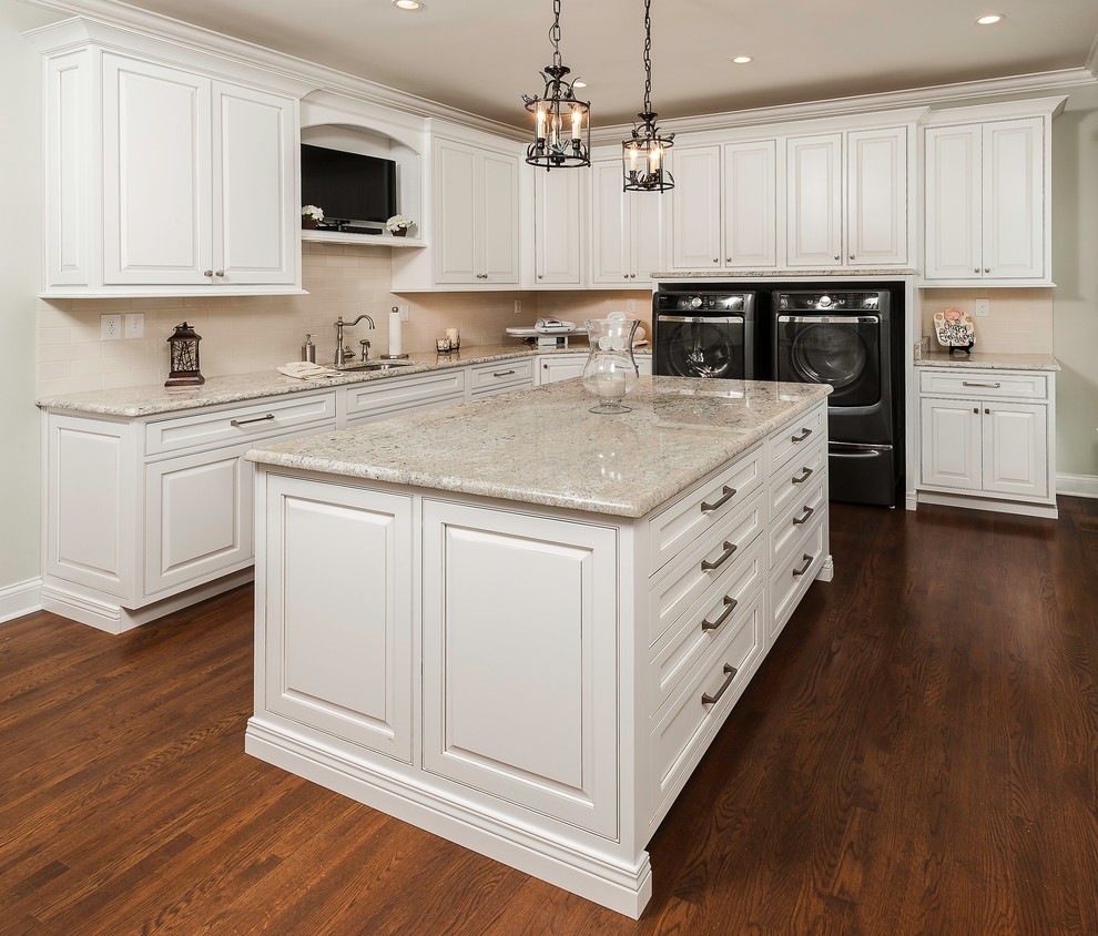 Photo of a traditional l-shaped utility room in Other with an undermount sink, raised-panel cabinets, white cabinets, beige walls, dark hardwood floors, a side-by-side washer and dryer and beige benchtop.