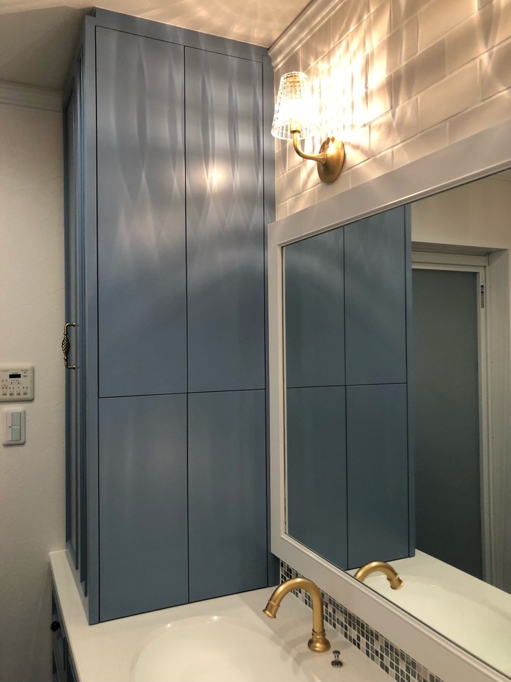 京都にあるトラディショナルスタイルのおしゃれなトイレ・洗面所 (家具調キャビネット、青いキャビネット、マルチカラーのタイル、モザイクタイル、白い壁、無垢フローリング、一体型シンク、人工大理石カウンター、茶色い床、白い洗面カウンター) の写真