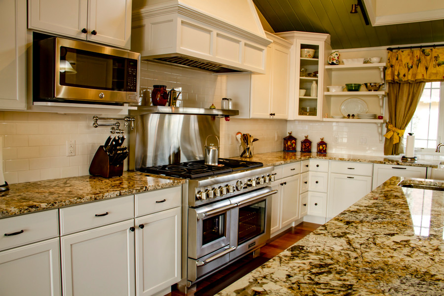 Large transitional u-shaped medium tone wood floor and brown floor open concept kitchen photo in Denver with a farmhouse sink, shaker cabinets, white cabinets, granite countertops, white backsplash, subway tile backsplash, stainless steel appliances and an island
