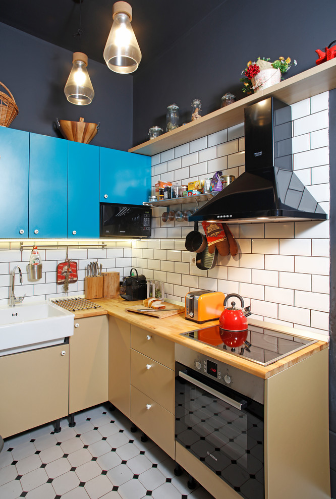 Inspiration for a small industrial l-shaped open plan kitchen in Other with flat-panel cabinets, turquoise cabinets, wood benchtops, black appliances, ceramic floors, no island, beige benchtop, a farmhouse sink, white splashback, subway tile splashback and multi-coloured floor.