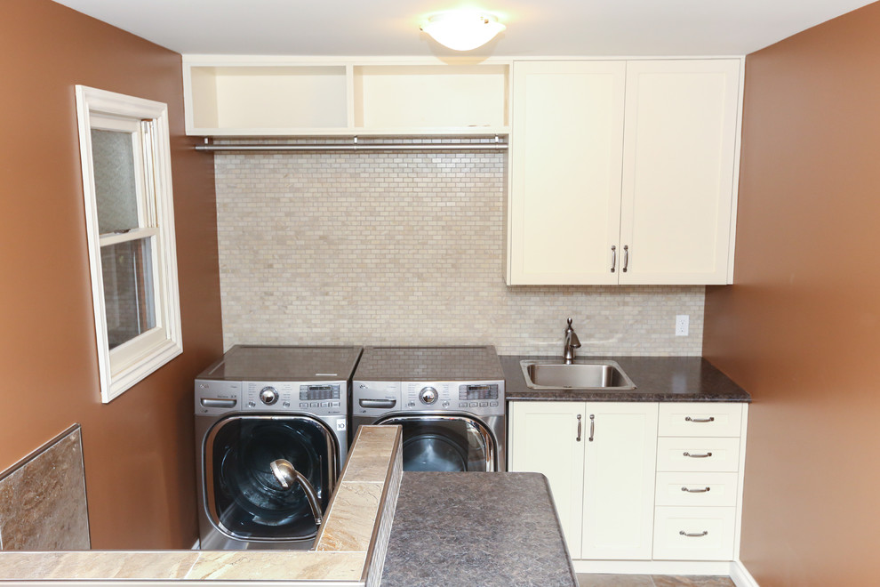 Photo of a mid-sized traditional galley utility room in Toronto with a drop-in sink, shaker cabinets, white cabinets, laminate benchtops, brown walls, porcelain floors, a side-by-side washer and dryer and grey floor.