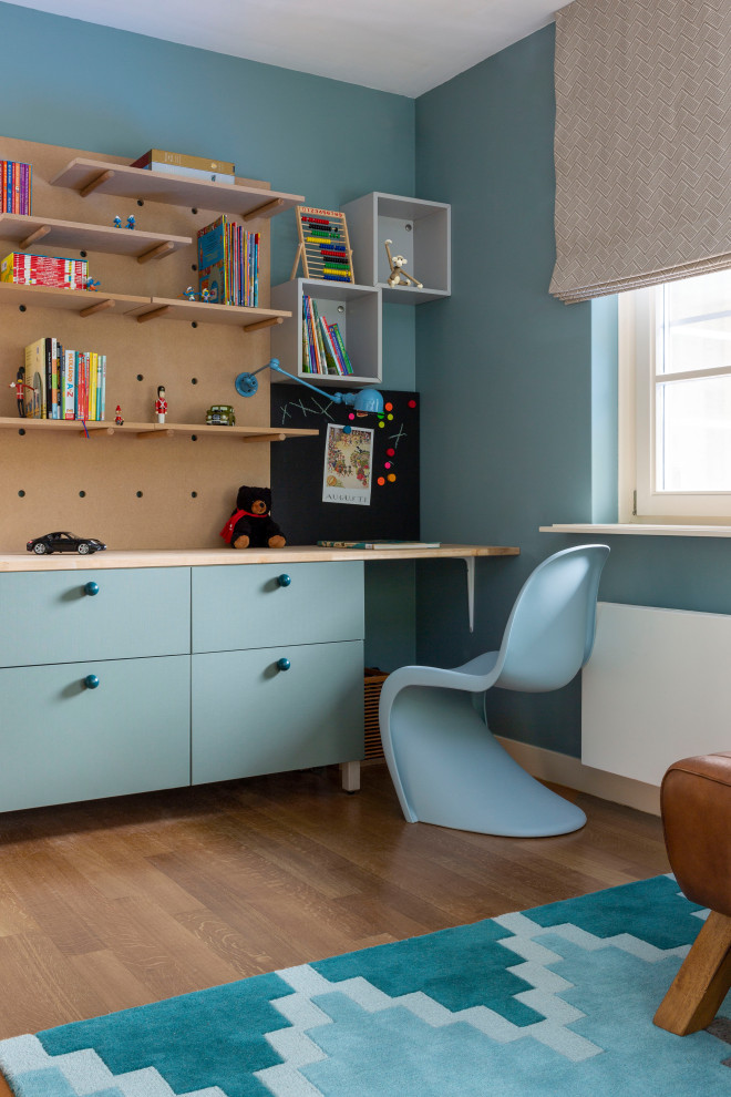 This is an example of a mid-sized transitional kids' bedroom for kids 4-10 years old and boys in Other with blue walls, light hardwood floors, brown floor and wallpaper.