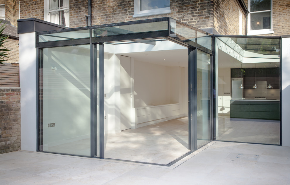 Sunroom in London with limestone floors, a glass ceiling and beige floor.