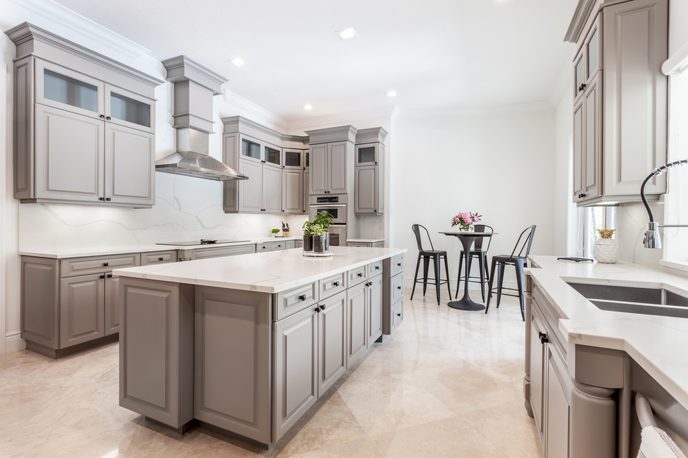 Large contemporary galley separate kitchen in Miami with an undermount sink, louvered cabinets, grey cabinets, quartz benchtops, white splashback, stone slab splashback, stainless steel appliances, marble floors, with island, beige floor and white benchtop.