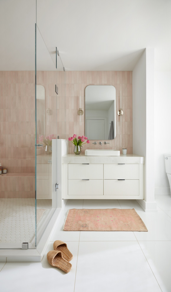 Пример оригинального дизайна: ванная комната среднего размера в современном стиле с плоскими фасадами, белыми фасадами, угловым душем, розовой плиткой, белыми стенами, душевой кабиной, настольной раковиной, белым полом, душем с распашными дверями, белой столешницей, тумбой под одну раковину и подвесной тумбой