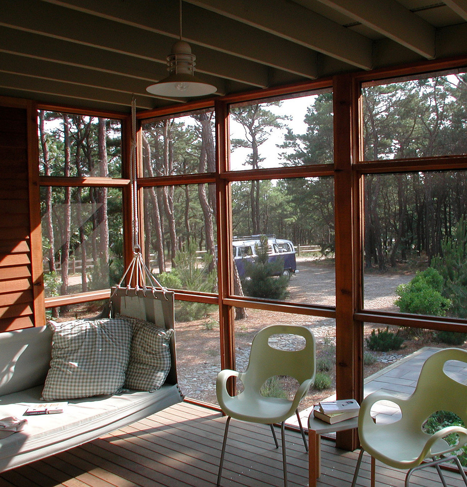 This is an example of an eclectic screened-in verandah in Boston with decking and a roof extension.
