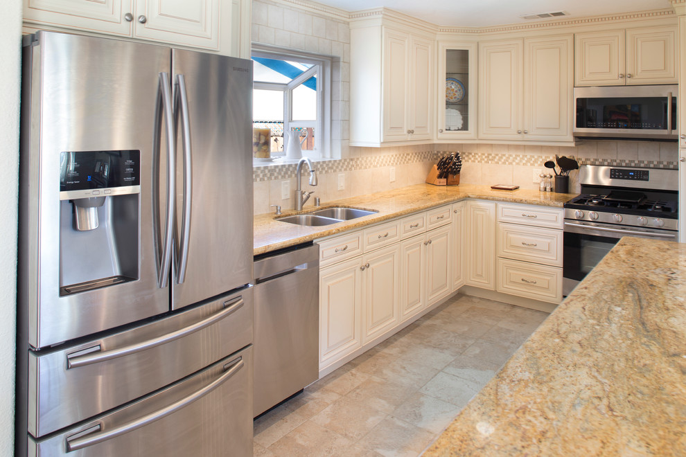 This is an example of a mid-sized traditional eat-in kitchen in San Francisco with a double-bowl sink, white splashback, ceramic splashback, stainless steel appliances, ceramic floors, with island, raised-panel cabinets, white cabinets and granite benchtops.