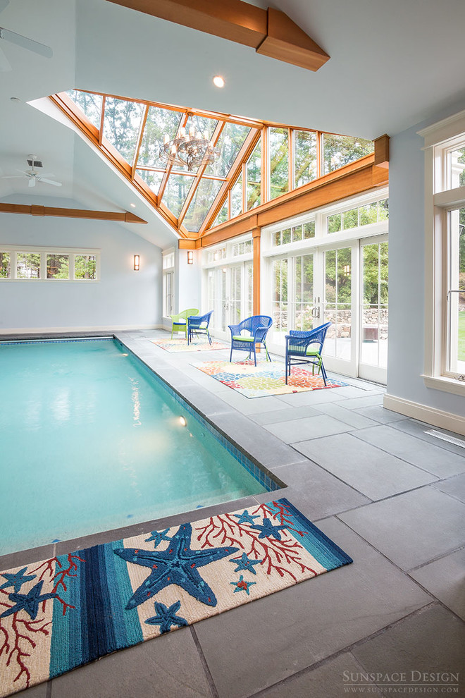Design ideas for an expansive traditional indoor custom-shaped pool in Boston with a pool house and natural stone pavers.