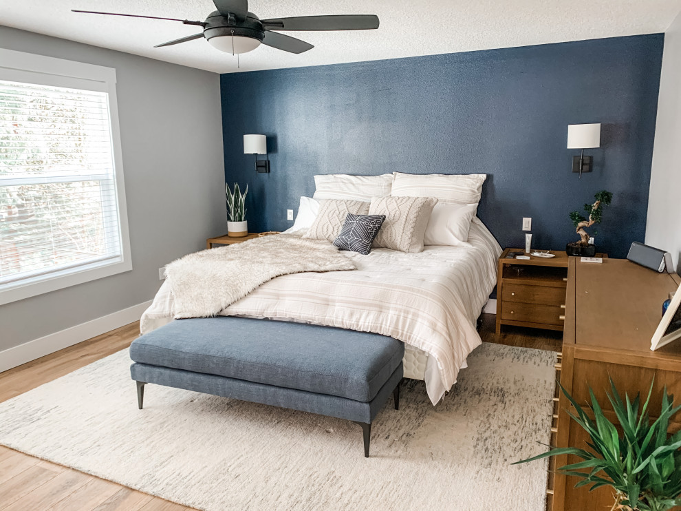 Aménagement d'une grande chambre parentale contemporaine avec un mur bleu, sol en stratifié et un sol marron.