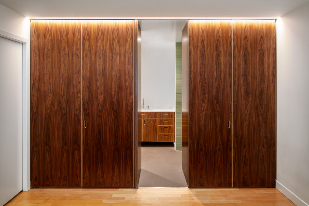 Retro Ankleidezimmer mit flächenbündigen Schrankfronten, hellbraunen Holzschränken und hellem Holzboden in San Francisco