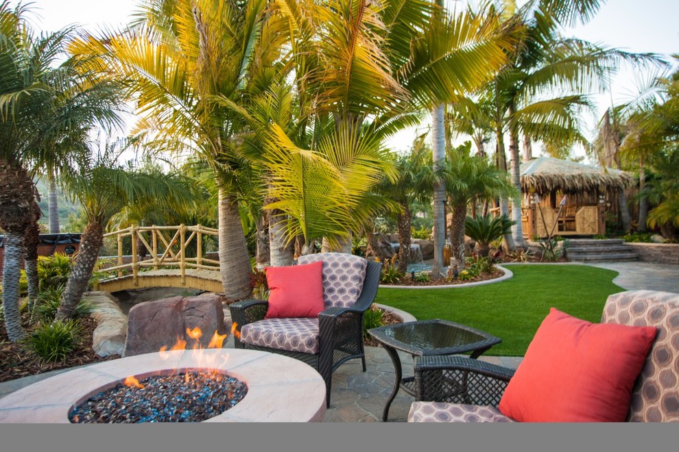 Inspiration for a large tropical backyard partial sun garden in San Diego with a fire feature and natural stone pavers.