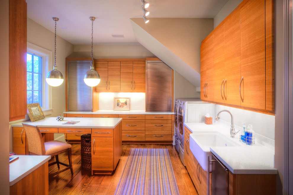 Design ideas for an expansive transitional utility room in Indianapolis with a farmhouse sink, flat-panel cabinets, medium wood cabinets, quartz benchtops, beige walls, a side-by-side washer and dryer and white benchtop.