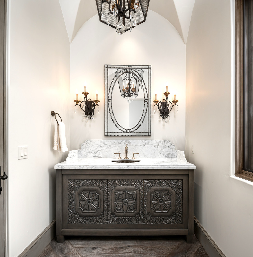 Photo of an expansive traditional powder room in Phoenix with furniture-like cabinets, grey cabinets, a one-piece toilet, multi-coloured tile, marble, white walls, dark hardwood floors, an undermount sink, marble benchtops, brown floor and multi-coloured benchtops.