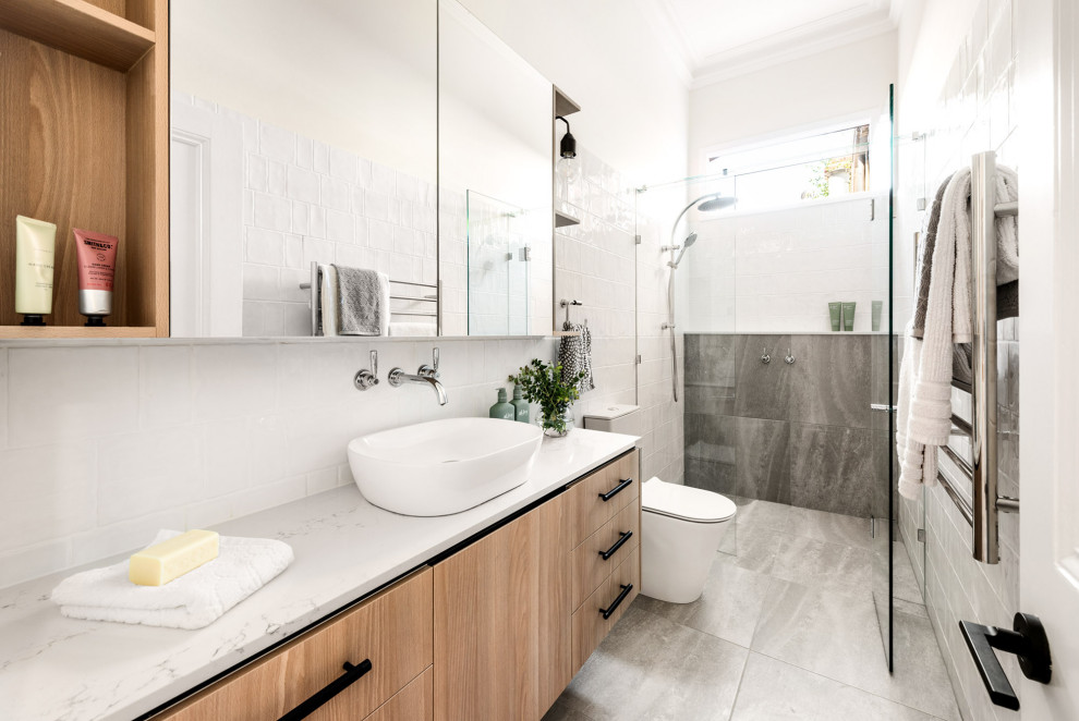 Inspiration for a transitional bathroom in Melbourne with flat-panel cabinets, medium wood cabinets, an alcove shower, gray tile, white tile, white walls, a vessel sink, grey floor, a hinged shower door, white benchtops, a single vanity and a floating vanity.