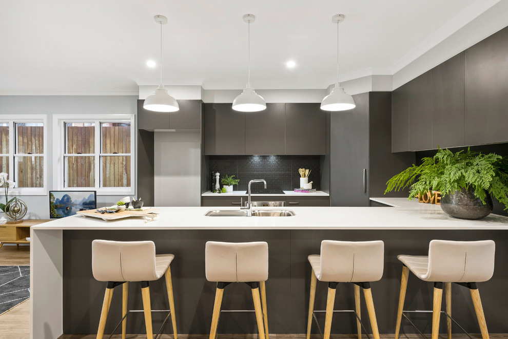 This is an example of a mid-sized contemporary u-shaped open plan kitchen in Other with a single-bowl sink, flat-panel cabinets, grey cabinets, laminate benchtops, grey splashback, ceramic splashback, stainless steel appliances, medium hardwood floors, with island, brown floor and white benchtop.