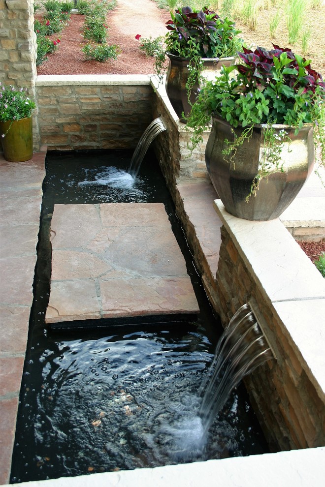 This is an example of a mediterranean side yard patio in Denver with a water feature and natural stone pavers.